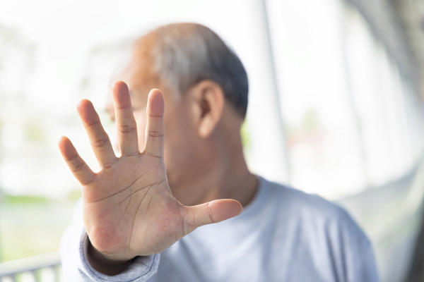 Ein Senior zeigt eine ablehnende Geste mit seiner Hand