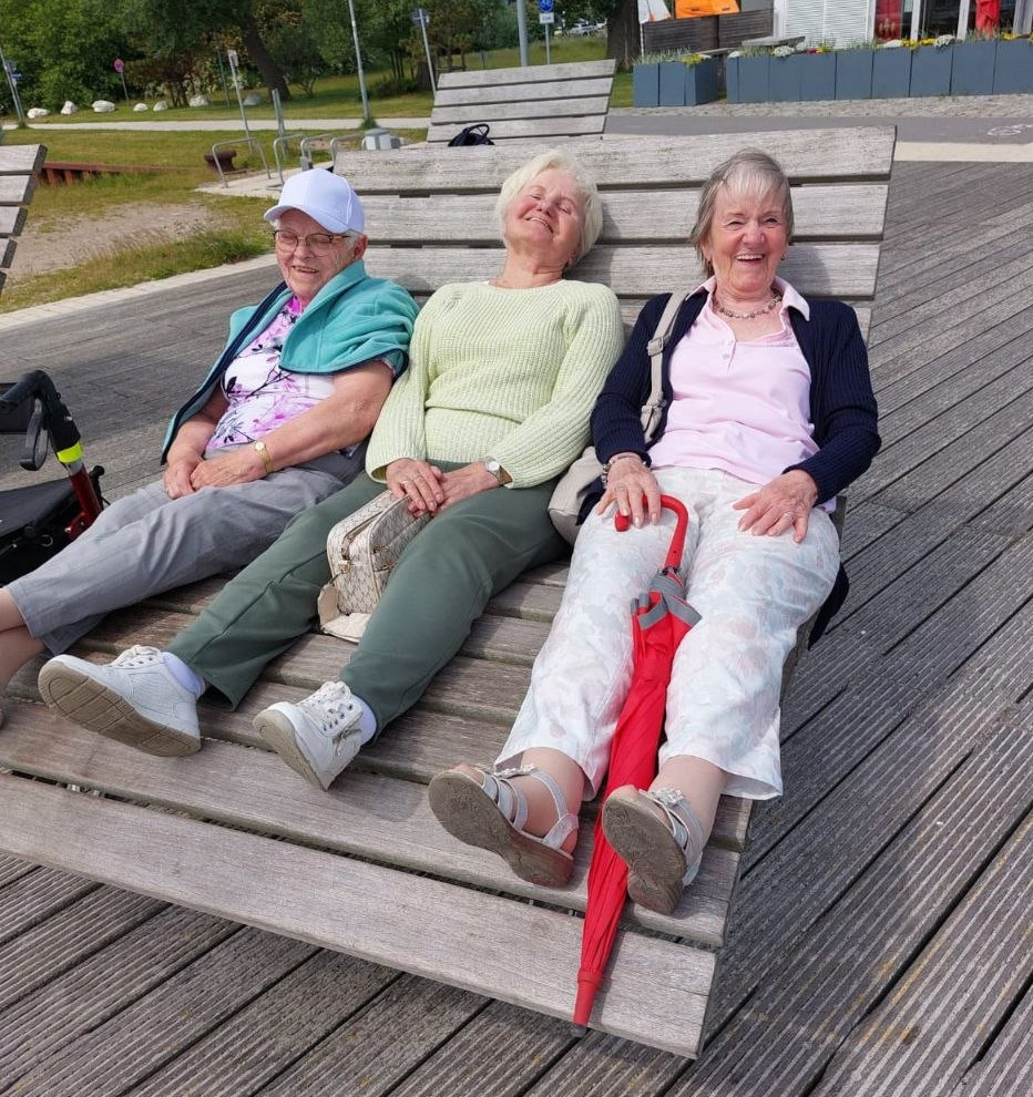 3 Senioren sitzen glücklich auf einer Bank