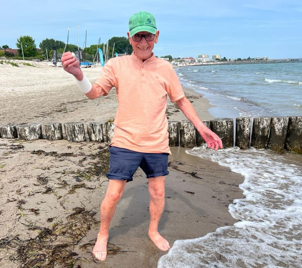 Ein Senior steht glücklich am Strand